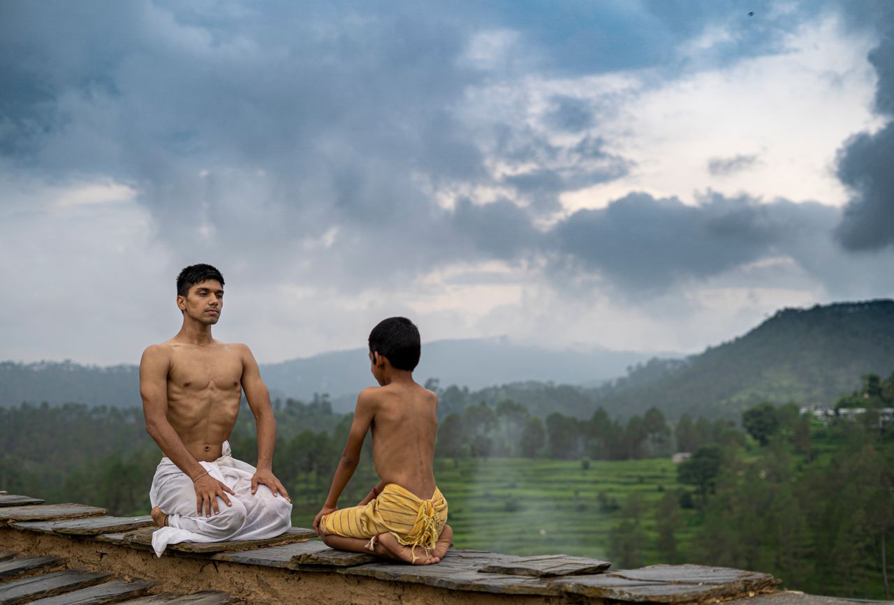 A man and a boy meditate outdoors on a scenic day, embracing serenity in nature.