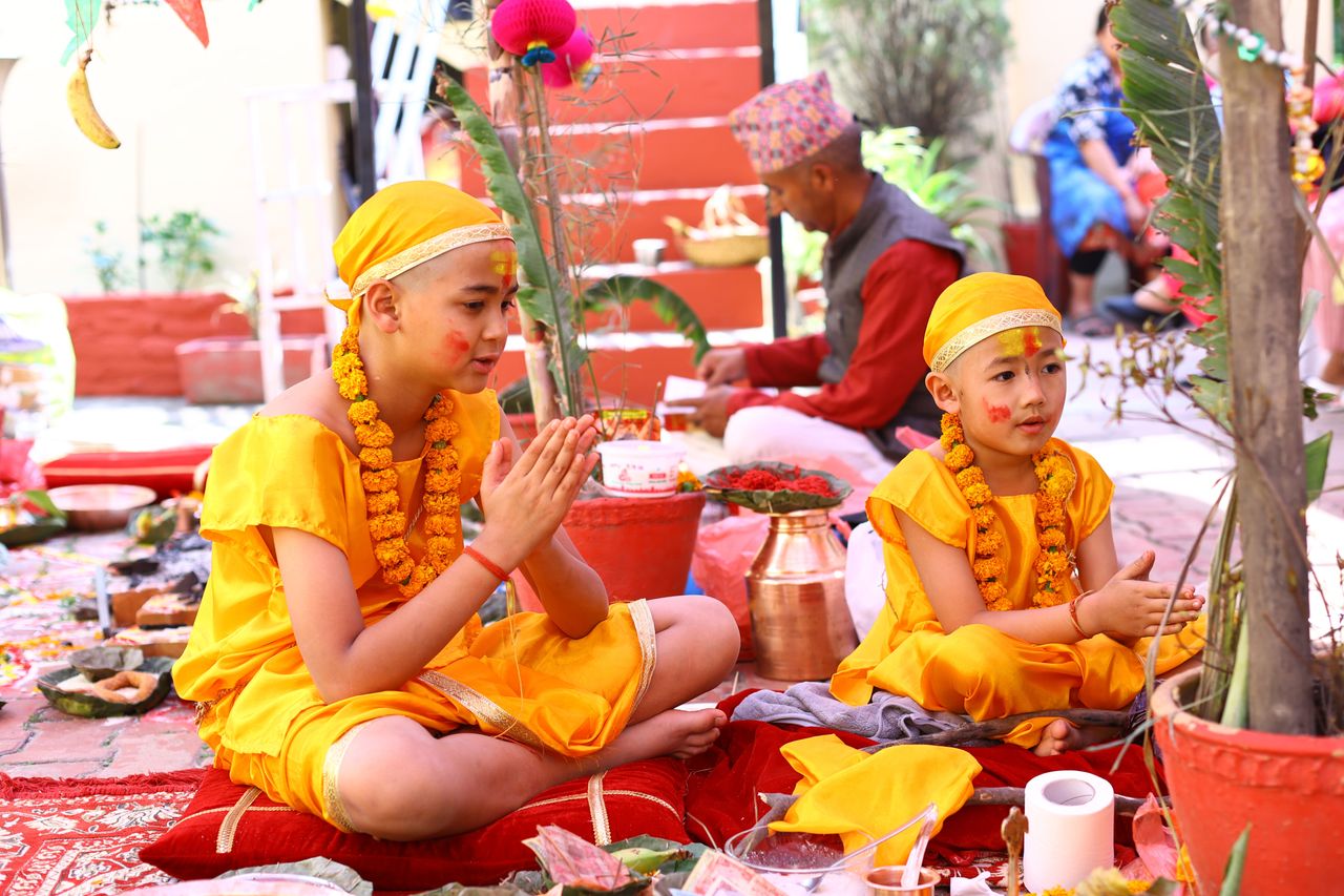 Children in yellow attire participate in a traditional Hindu ceremony with vibrant decorations.